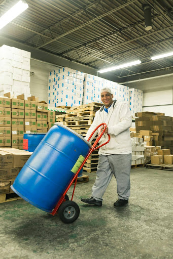 A warehouse employee moving a drum of regulated material through a facility, illustrating the classification, packaging, and shipping operations that PE due diligence teams routinely miss during hazmat compliance review.
